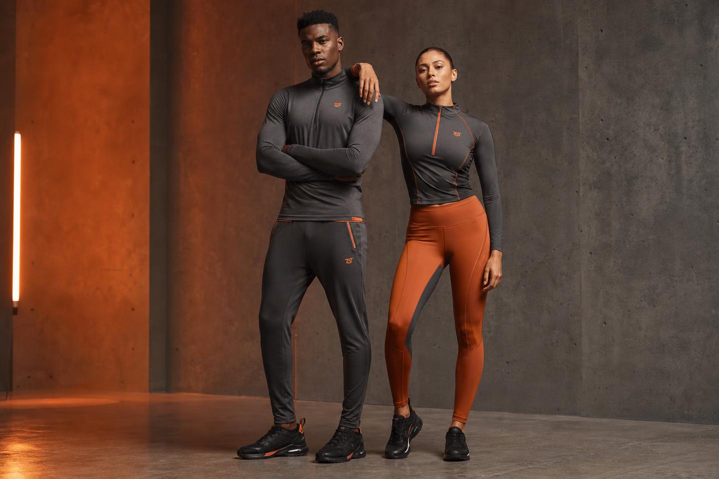 Male and female models wearing FIT premium charcoal and ember athletic wear